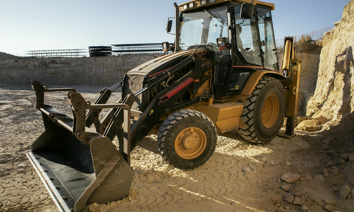 Backhoe loader carrying material across a civil construction site